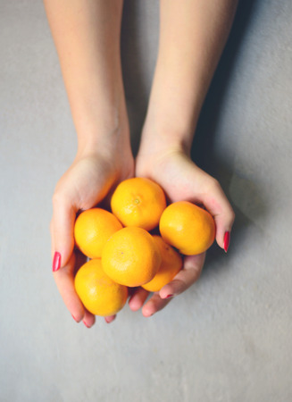 Hands holding ripe of fresh mandarines - Top viewの写真素材