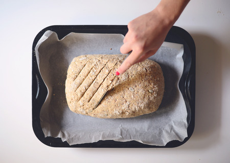 Woman hands making lines on fresh loaf of doughの写真素材