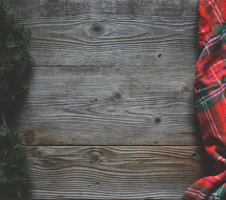 Flat lay of scarf with Christmas tartan texture and branch of tree on wooden background with space in middle - Christmas or New Year backgroundの写真素材
