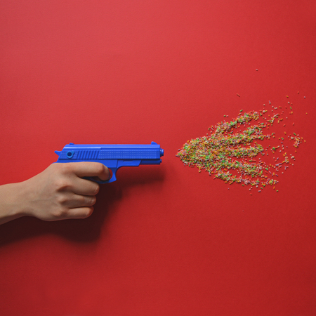 Hand holding pistol and firing multicolored candy - Flat layの写真素材