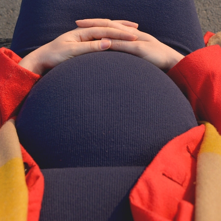 Woman holding her hands on stomach outdoor in park - Pregnancy conceptの写真素材