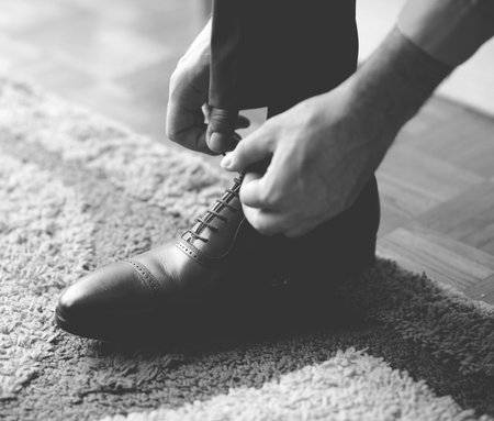 Man tying the laces on black shoes - Black and white photograph in mat toneの写真素材
