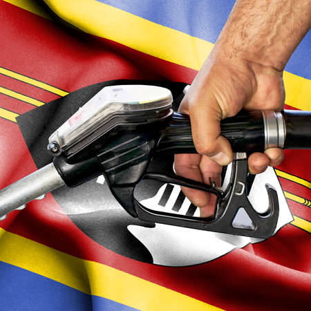 Gasoline consumption concept - Hand holding hose against flag of Swazilandの写真素材