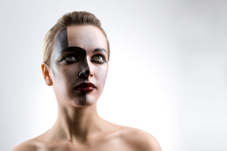 Beautiful blond young Caucasian woman with contrast make-up on gray