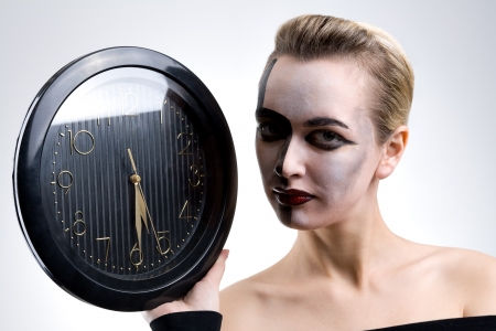 Beautiful woman holding big clock on grayの写真素材