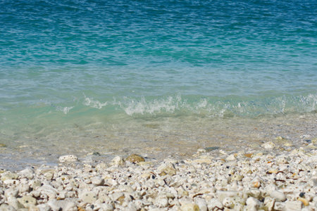 White pebble beach with small blue waves