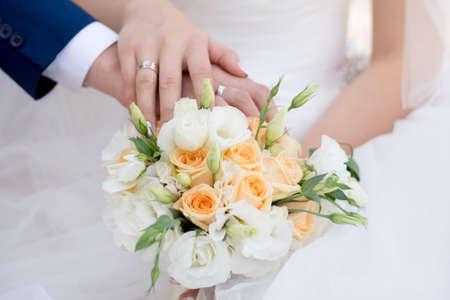 Hands and rings of the bride and groom on wedding bouquetの写真素材