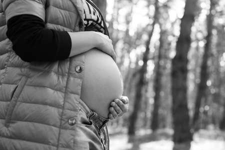 Profile of pregnant woman hugging her belly in the forest. Future mother holding her stomach with love. Pregnancy, maternity, family conceptの写真素材