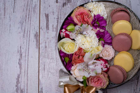 Box with fresh flowers and macaroons on wooden background, top view, with space for textの写真素材