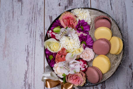 Box with fresh flowers and macaroons on wooden background, top view, with space for textの写真素材