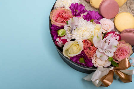 Box with flowers and macaroons on blue background, top view, with space for textの写真素材
