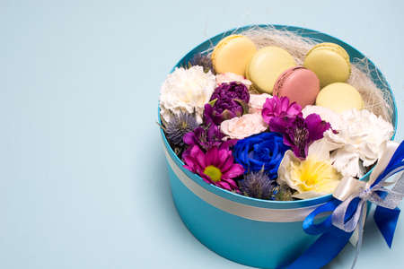 Box with flowers and macaroons on blue background, top view, with space for textの写真素材