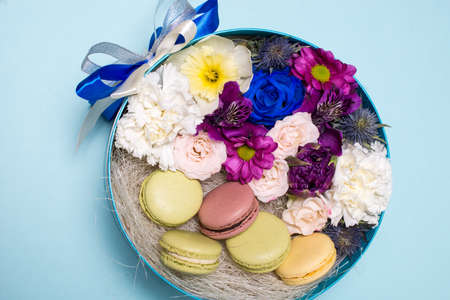 Box with flowers and macaroons on blue background, top viewの写真素材