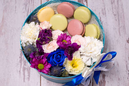 Box with fresh flowers and macaroons on wooden background, top viewの写真素材