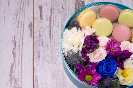 Box with fresh flowers and macaroons on wooden background, top view, with space for textの写真素材