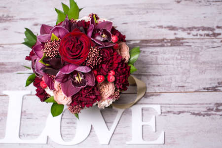 beautiful flower arrangement with the inscription LOVE on the shabby wooden table with space for textの写真素材