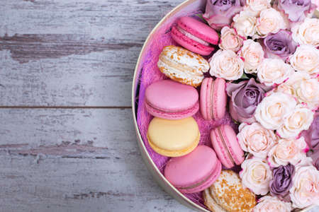 Box with fresh flowers and macaroons on wooden background, top view, with space for textの写真素材