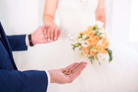 Groom holding wedding rings on the palm, the groom in a blue suit, groom holding wedding rings, grooms hand holding a ring, wedding ring in groom handの写真素材