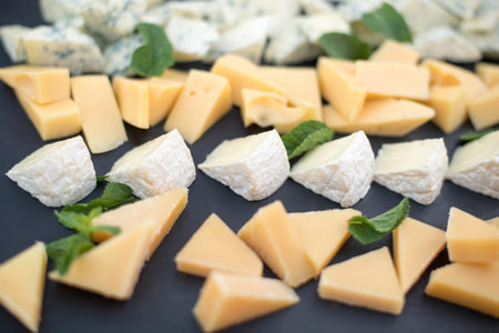 Different types of cheeses on black board. Selective focus.yieldの写真素材