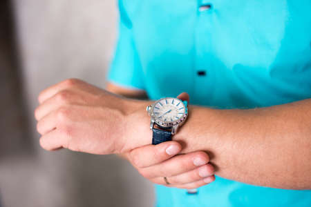 Business man adjusting his watch, on a grey background, stock picture.の写真素材