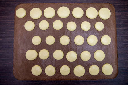 cooking, baking, confectionery and people concept - chef with macarons on oven tray at bakery kitchen.の写真素材