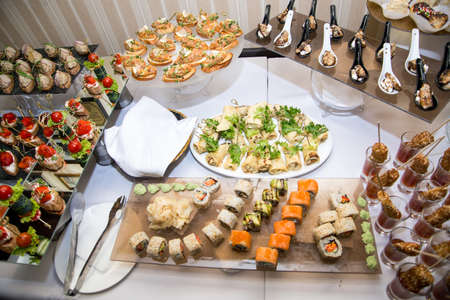 Buffet table of reception with burgers, cold snacks, meat and salads. Sushi. Selective focus.の写真素材