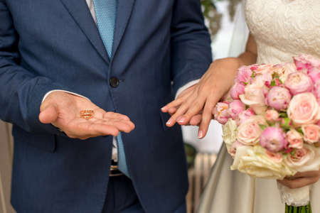 Hands and rings of the bride and groom on wedding bouquetの写真素材