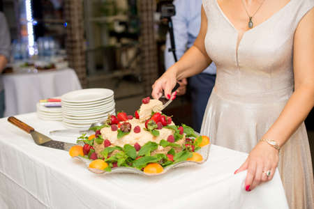 girl cuts cake with strawberries, peachand raspberries.の写真素材