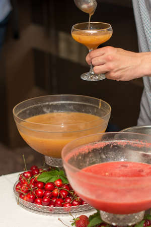 cocktail in a glass of champagne, punch and fruit in the background.の写真素材
