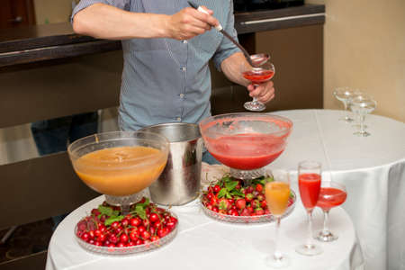 cocktail in a glass of champagne, punch and fruit in the background.の写真素材