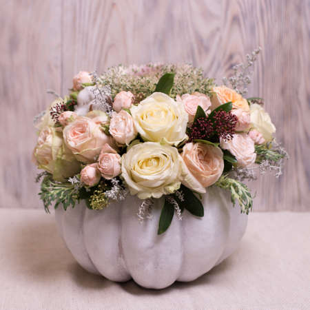floral bouquet in a white pumpkin on a light background, a mixture of flowers, peony rose, eucalyptus, chrysanthemum, Brassica, white orchid, cotton.の写真素材