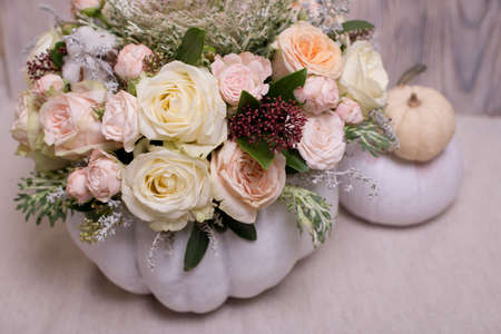 floral bouquet in a white pumpkin on a light background, a mixture of flowers, peony rose, eucalyptus, chrysanthemum, Brassica, white orchid, cotton.の写真素材