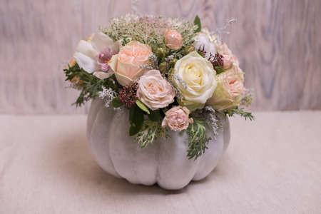 floral bouquet in a white pumpkin on a light background, a mixture of flowers, peony rose, eucalyptus, chrysanthemum, Brassica, white orchid, cotton.の写真素材
