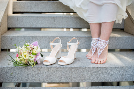 Closeup of bride feet shoes and wedding bouquet of flowers.の写真素材