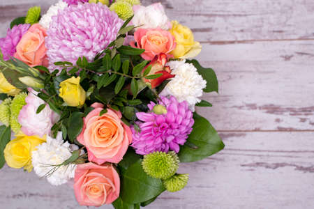 beautiful floral arrangement in the box, pink and yellow rose, pink eustoma, green and pink chrysanthemum, white carnation, dahlia on wooden background, top view, with space for textの写真素材