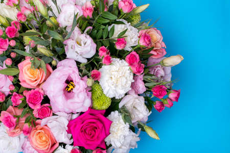beautiful floral arrangement, pink and yellow rose, pink eustoma, green and pink chrysanthemum, white carnation, pink dahlia on a blue, turquoise background with space for text.の写真素材