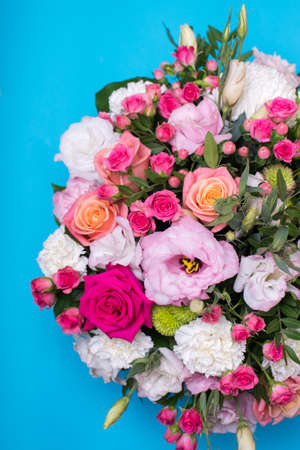 beautiful floral arrangement, pink and yellow rose, pink eustoma, green and pink chrysanthemum, white carnation, pink dahlia on a blue, turquoise background with space for text.の写真素材