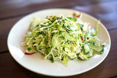 spring salad with cabbage cucumbers and radishes on a wooden backgroundの写真素材