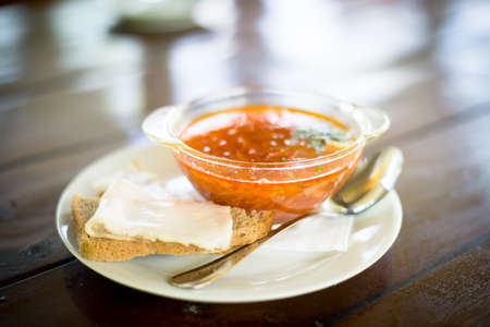 Sour cream, sandwich with salted lard, borscht with parsley and sour cream in white plate, spoon on wooden table. Top viewの写真素材