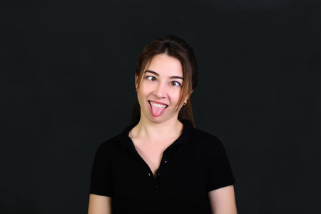 fun girl on black background looking at nose making make funny faces.の写真素材