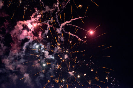 A few volleys of festive fireworks in the night sky, red-yellow.の写真素材