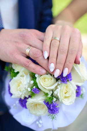 Hands and rings on wedding bouquet.の写真素材