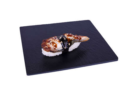 Traditional fresh japanese sushi on black stone Nigiri unagi on a white background. Gunkan ingredients: eel, unagi sauce, nori, rice, sesame seedsの写真素材