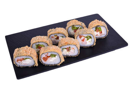 Traditional fresh japanese sushi on black stone Warm roll caesar on a white background. Roll ingredients: smoked chicken fillet, philadelphia cheese, tomato, lettuce, nori, rice, panko crackersの写真素材