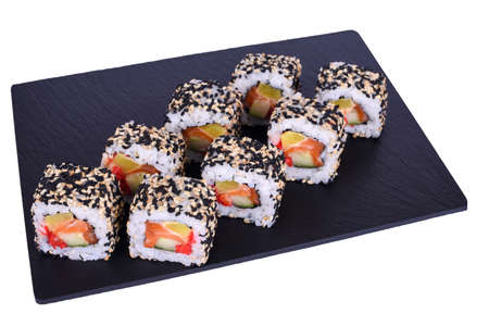 Traditional fresh japanese sushi rolls on a black stone Kyoto on a white background. Roll ingredients: salmon, daikon radish, cucumber, red tobiko, spicy sauce, nori, rice, sesame mixの写真素材