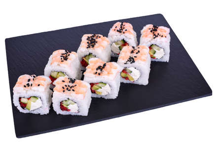 Traditional fresh japanese sushi rolls on a black stone Ebi Dragon on a white background. Roll ingredients: tiger shrimp, philadelphia cheese, avocado, red tobiko caviar, black sesame, nori, riceの写真素材