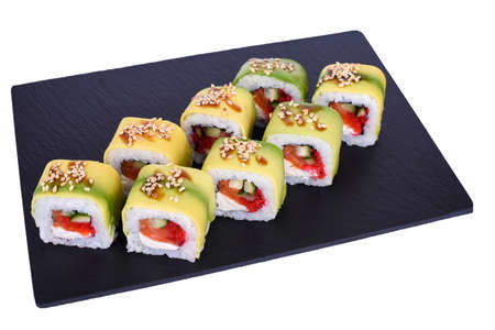 Traditional fresh japanese sushi rolls on a black stone Green Dragon on a white background. Roll ingredients: avocado, salmon, philadelphia cheese, cucumber, red tobiko caviar, unagi sauce, sesame mix, nori, riceの写真素材