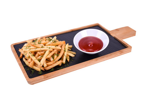 French fries with herbs and ketchup on a wooden board isolated on a white background