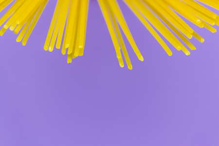 long yellow spaghetti pasta on violet background. Yellow Italian pasta. Italian food and kitchen concept. copy spaceの写真素材