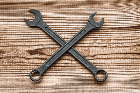 black steel wrenches lies by crosswise layout on dark brown wood textured background with copy spaceの写真素材